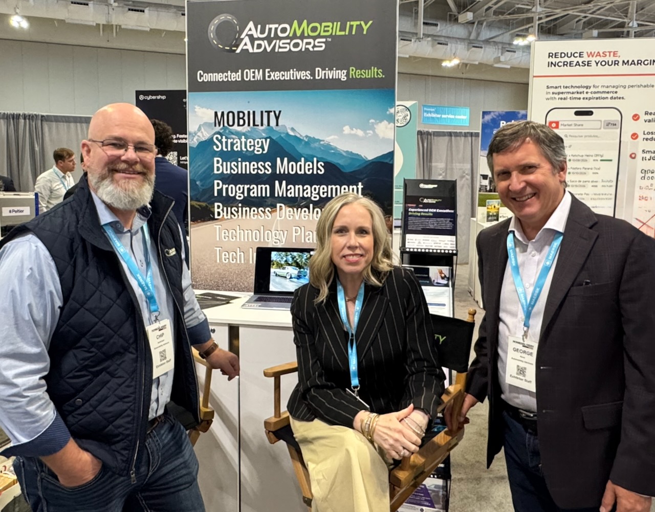 AutoMobility Advisors OEM executives — Chip Goetzinger and George Ayres with a colleague — at the AMA booth showcasing mobility strategy, business models, program management, and technology planning services.